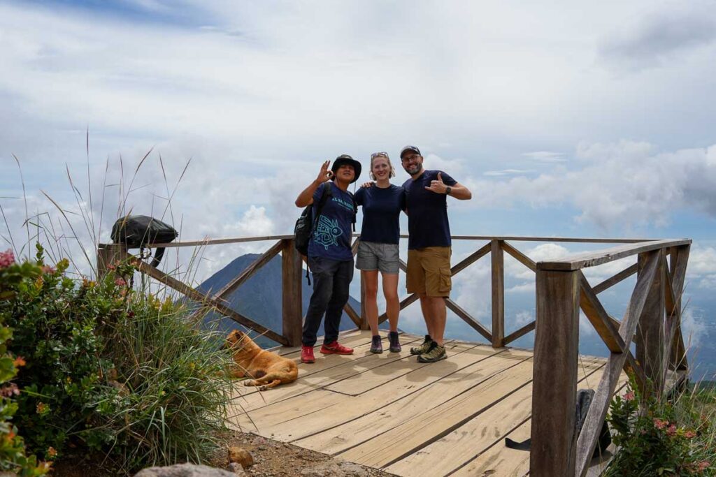Posing with our local guide on the misty trail up Santa Ana Volcano, with another volcano in the background. ©KettiWilhelm2023