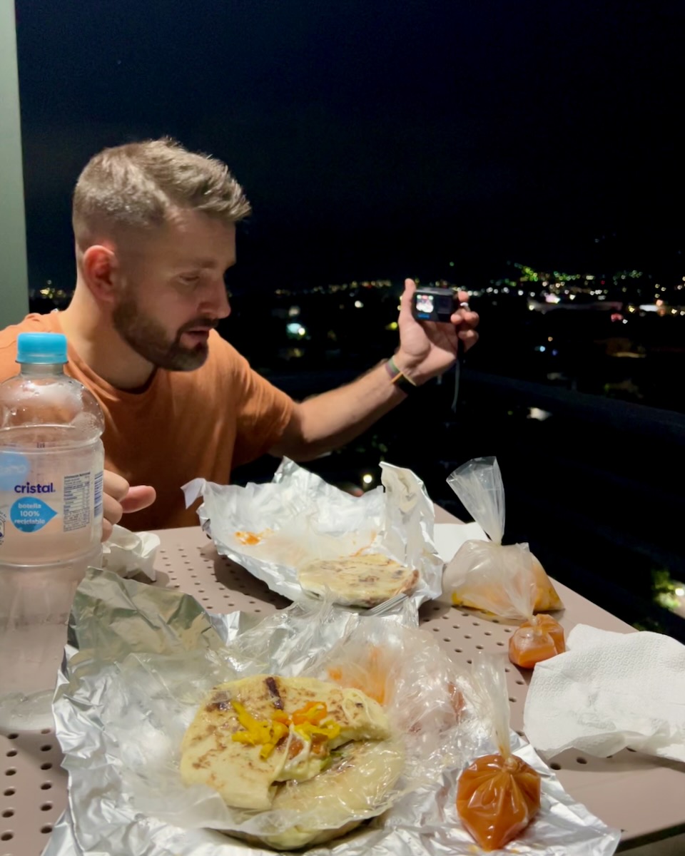 Eating pupusas to-go on the balcony of our hotel in San Salvador, with a plastic bottle of water and lots of excessive packaging. ©KettiWilhelm2023