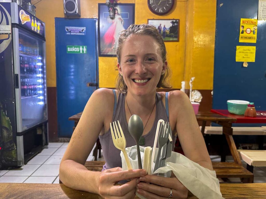 The author of this real life test of LARQ and Grayl filter travel water bottles in a restaurant in El Salvador, holding up her set of plastic forks that she reuses in order to reduce waste while traveling. ©KettiWilhelm2023