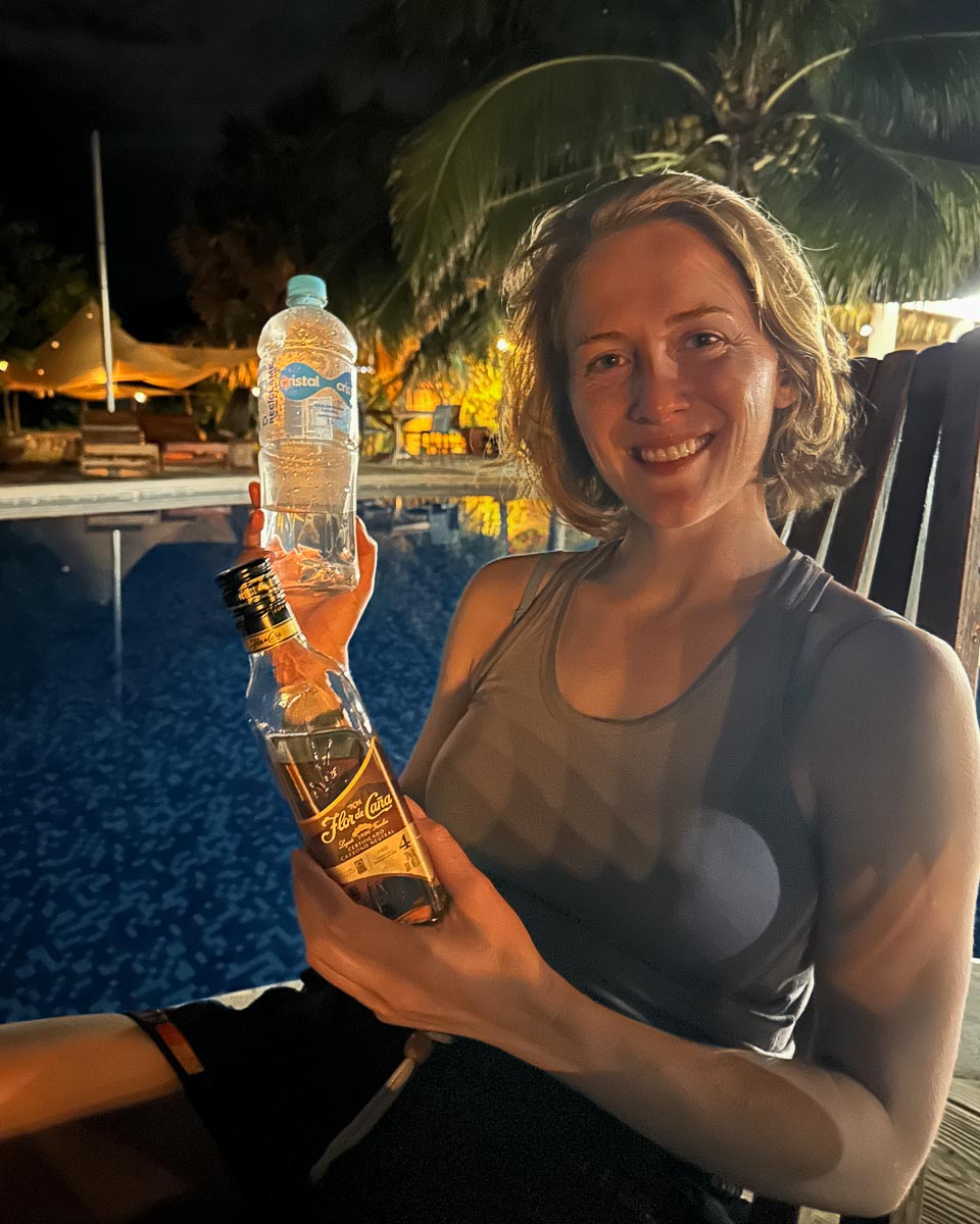 Holding a bottle of Flor de Caña rum, and the only plastic water bottle I bought during a 10-day trip to El Salvador, in Central America, while purifying my own tap water for travel. ©KettiWilhelm2023