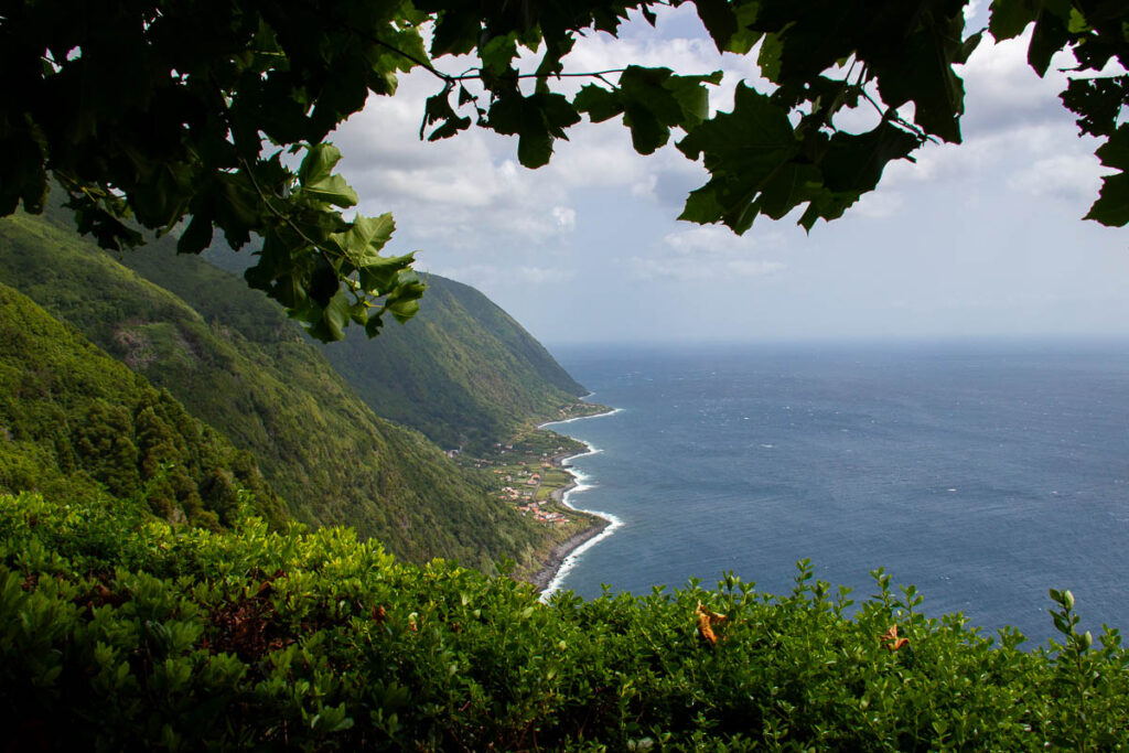 ALT Steep green mountains on the island of São Jorge, Azores, lead straight into the waters of the Atlantic, with orange-roofed buildings at the coast in between. ©KettiWilhelm2024