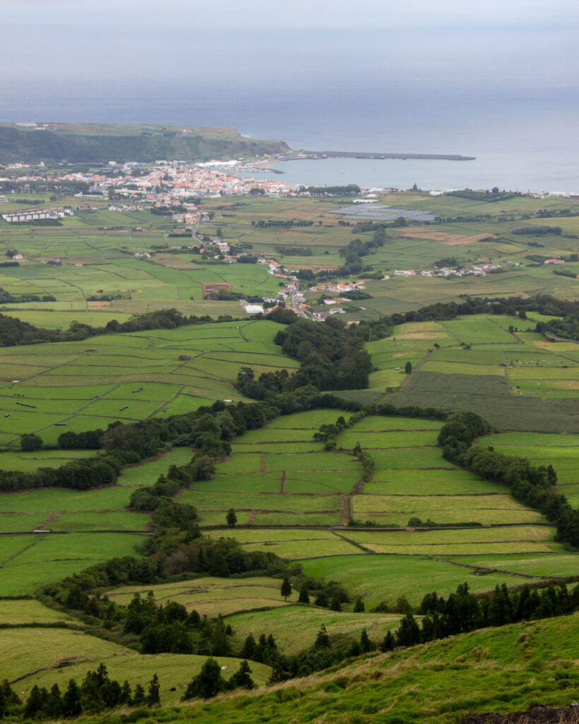 Low walls made of local volcanic rock divide farm fields on Terceira, in the Azores, Portugal, with the Atlantic Ocean visible in the distance. ©KettiWilhelm2024