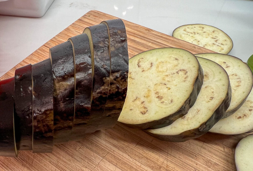 An organic eggplant, delivered by Misfits Market, sliced on a cutting board. It was covered in bruises on the outside – the reason it was rejected from grocery stores – but looks perfectly good on the inside. ©KettiWilhelm2024