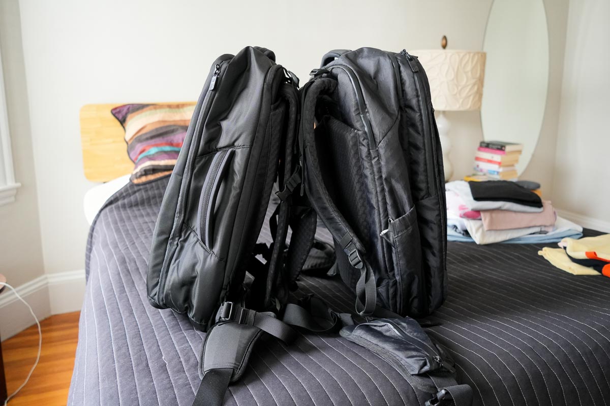 Two of the best backpacks for travel, leaning against each other on the review writer's bed: the Travel Backpack Pro, and the Travel Backpack Lite, both made by Tortuga. ©KettiWilhelm2024