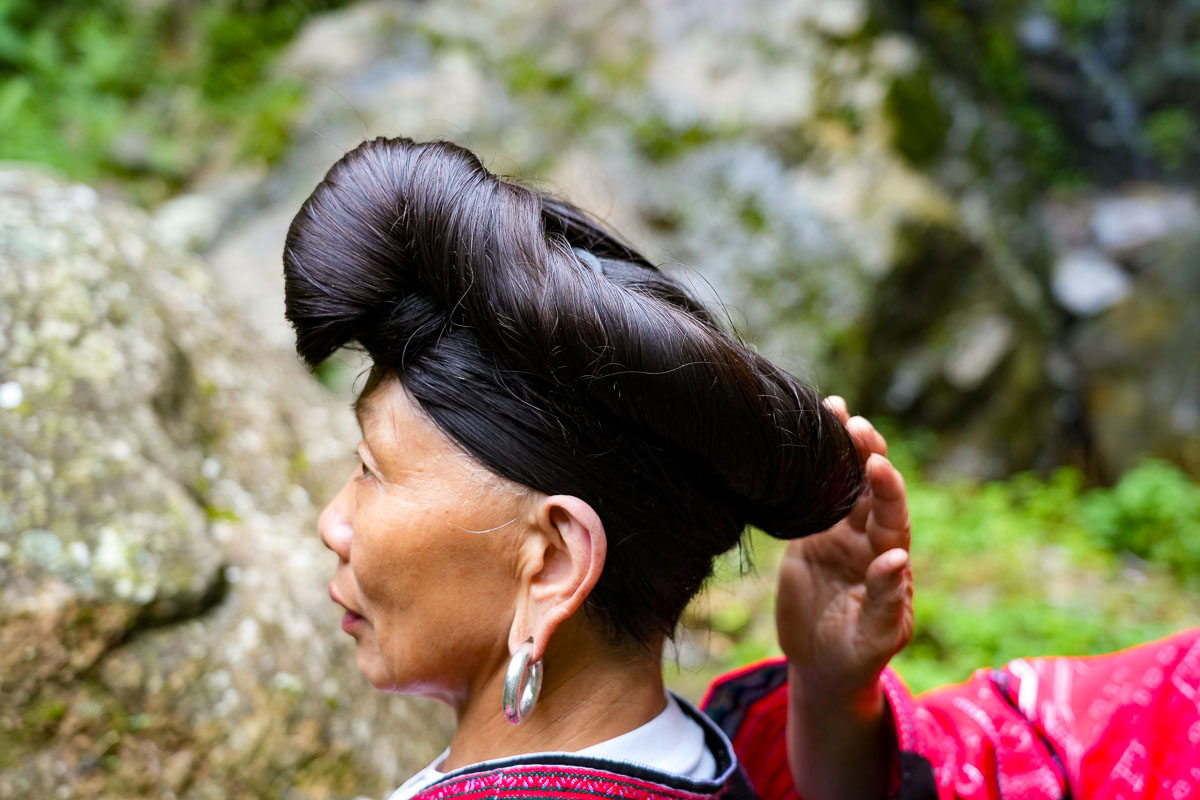 A Red Yao woman adjusting the hair style of another Red Yao woman during an indigenous tour of Longsheng, Guangxi, China. ©KettiWilhelm2025