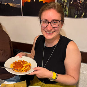 One of our guests on an e-bike trip in the Marche region, Italy, holding her plate of gluten-free pasta at dinner. ©KettiWilhelm2025