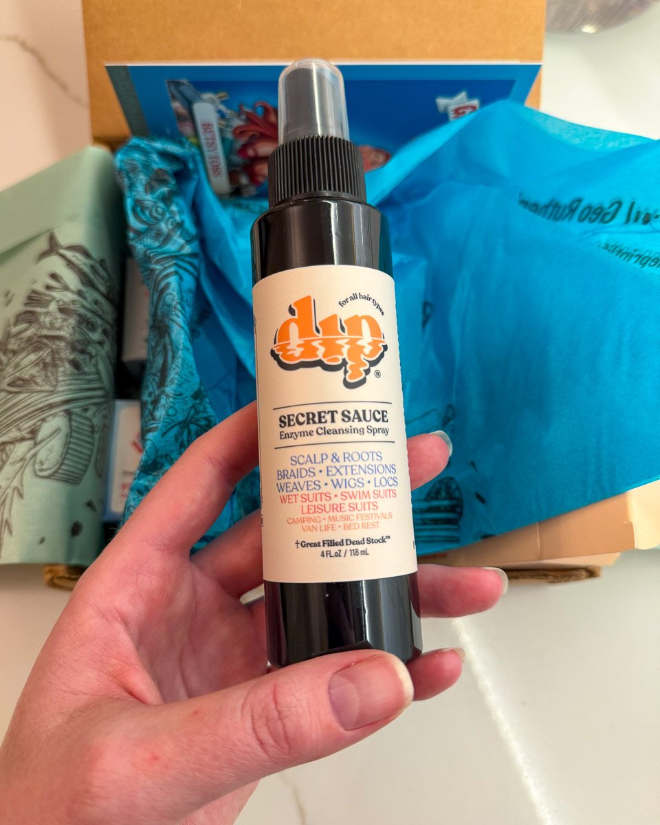 Unboxing my Secret Sauce Enzyme Cleansing Spray from Dip haircare, which is packaged in a dark-colored, deadstock plastic spray bottle that was rescued from a landfill. ©KettiWilhelm2025