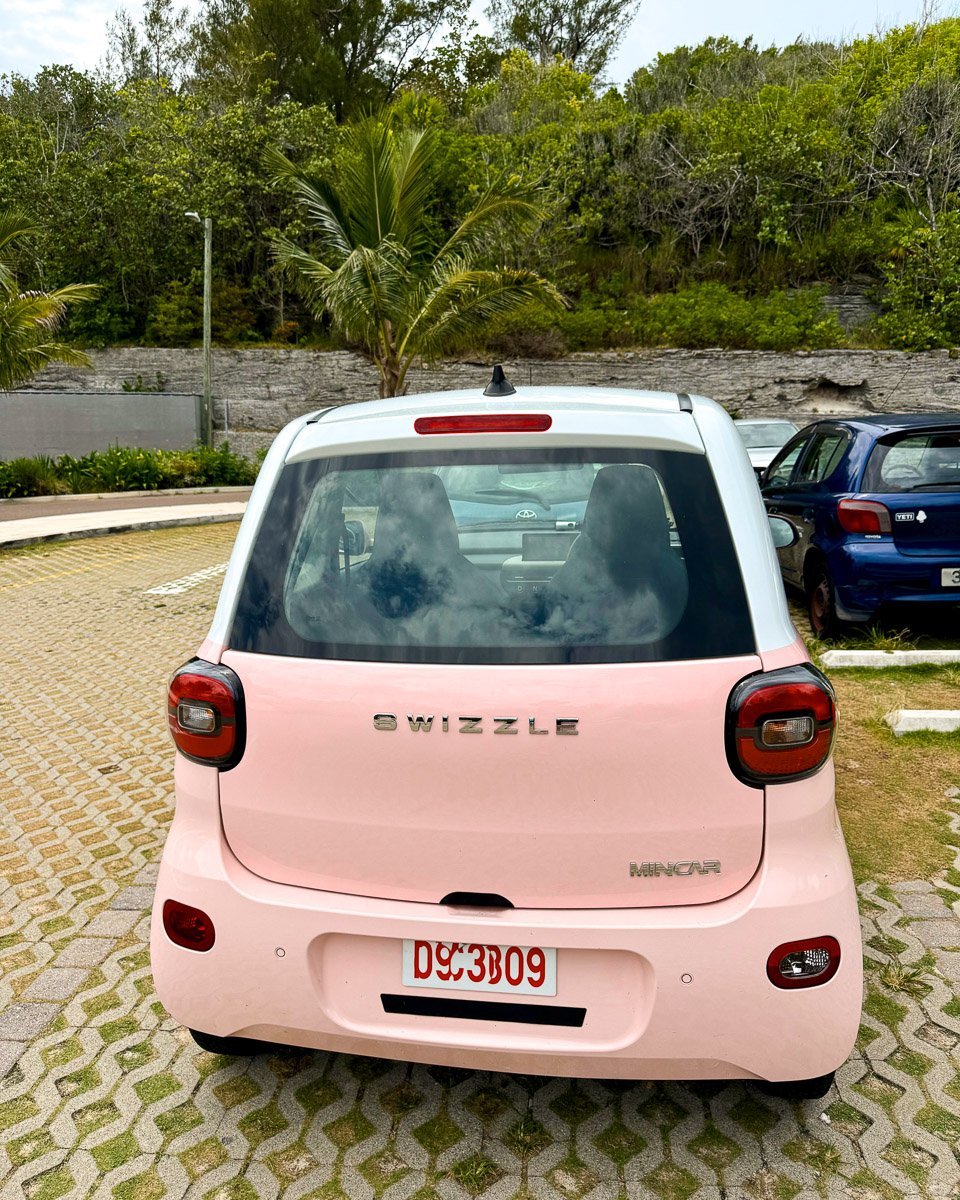 Small pink elective vehicle parked at the parking lot of Horseshoe Beach in Bermuda. ©KettiWilhelm2025