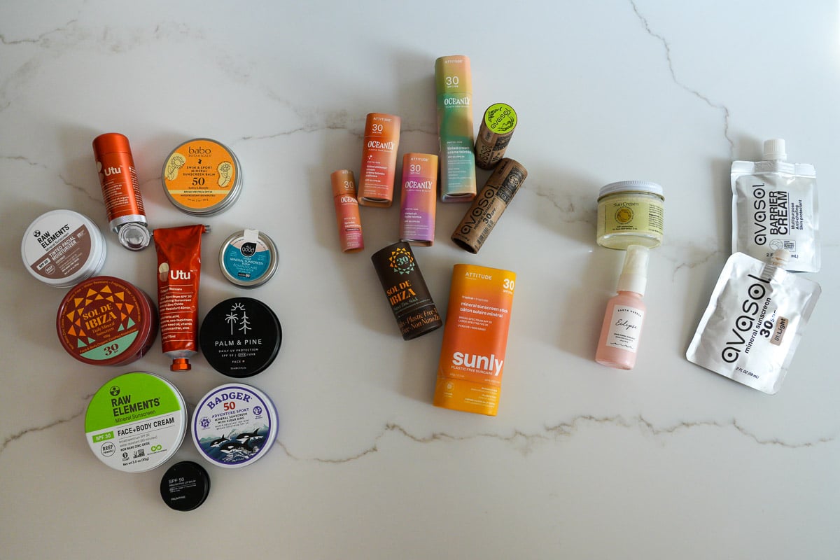 My collection of organic sunscreen sticks, tubes and jars from 11 plastic-free sunscreen brands: Avasol, Raw Elements, Palm and Pine, Utu, Circular Bodies, All Good, Badger, Babo Botanicals, ATTITUDE, Earth Harbor and Sol de Ibiza. ©KettiWilhelm2025