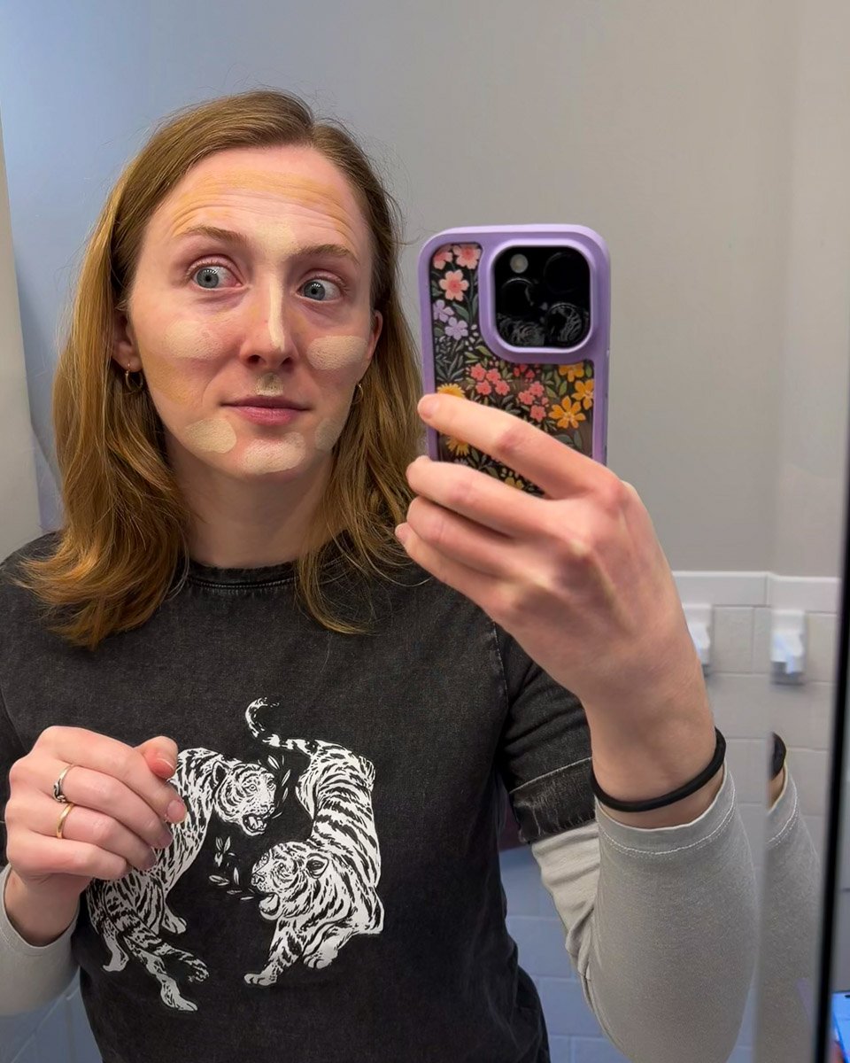 The author of this review, a white woman in her 30s, looks in the mirror at the streaks of two different shades of Avasol mineral sunscreens on her face. ©KettiWilhelm2025