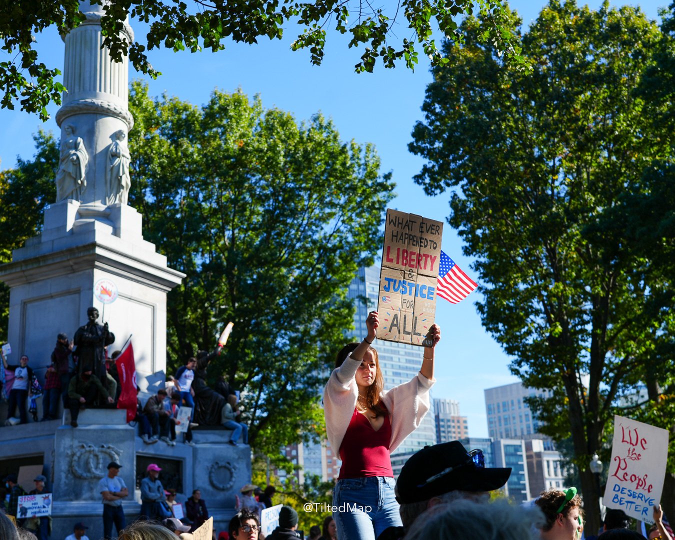 A young woman holds a sign reading "whatever happened to liberty and justice for all" along with a US flag, during the No Kings protest against President Donald Trump and ICE in Boston in October, 2025. ©KettiWilhelm2025