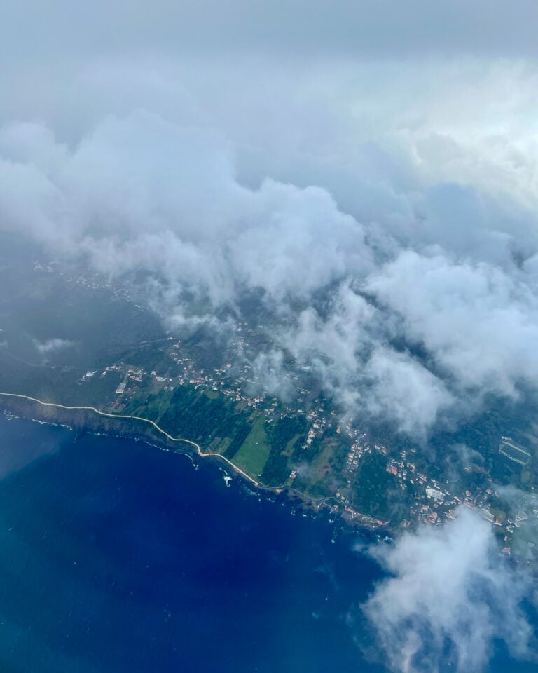 Window seat view looking down at fluffy white clouds and coast line of the Azores islands, Portugal. ©KettiWilhelm2026