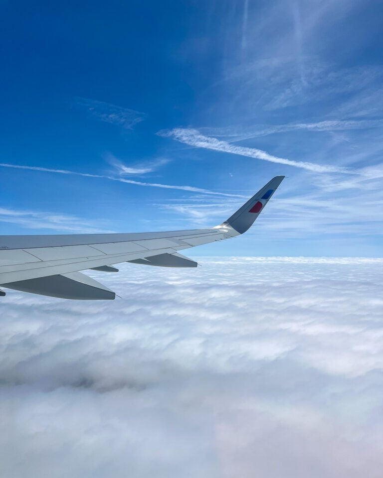 Jet contrails over a blue sky seen from the window seat of another airplane. ©KettiWilhelm2026