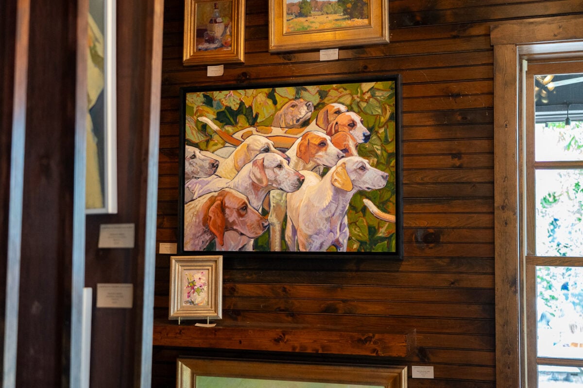 “In the Catalpas,” an oil on canvas painting of dogs by artist Leslie Shiels, hangs on the wall at Leiper's Creek Gallery in Leiper's Fork, Tennessee, a must-see spot when visiting Franklin, TN. ©KettiWilhelm2026