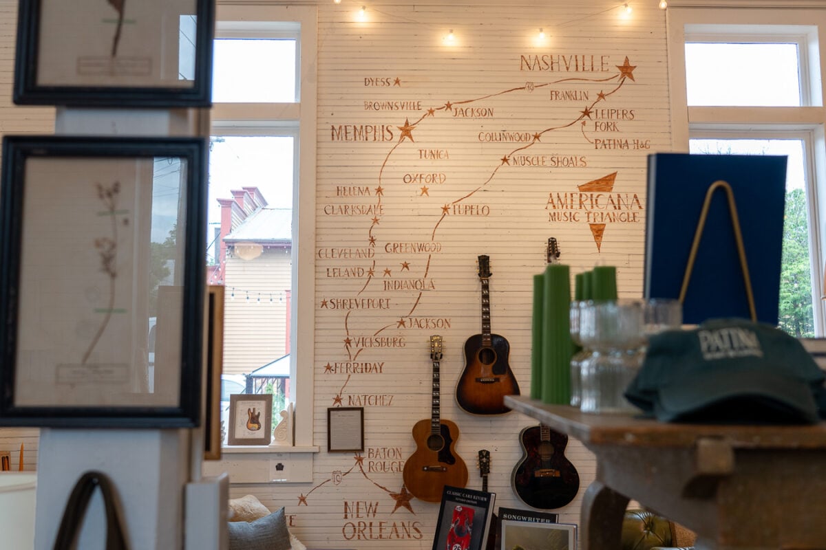 The famous "pickin corner" displays rare and unique guitars that anyone can play, on a wall with a hand painted map of the Americana Music Triangle, at the local gift shop Patina Home & Garden, in Leiper's Fork, Tennessee. ©KettiWilhelm2026